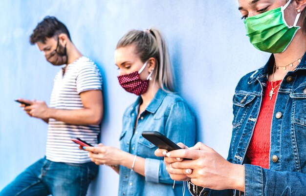 Milenial friends using mobile phone covered by face mask