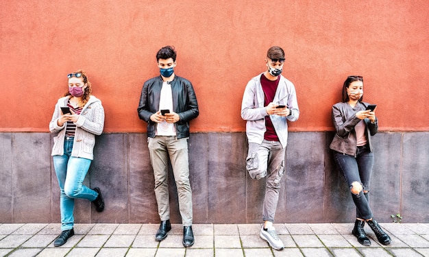 Milenial persone che utilizzano smartphone mobile coperto da maschera facciale