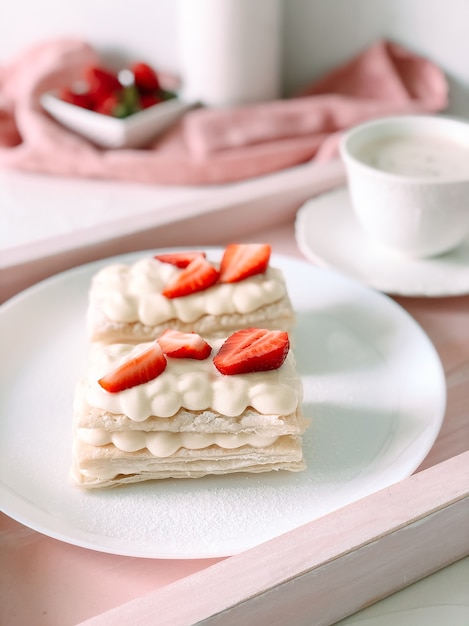 Torta milfey con panna e fragole e tazza di caffè