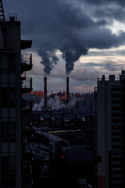 Milieu- en luchtvervuiling, concept van ecologische problemen. Rook uit fabrieksschoorstenen tegen een grijze bewolkte hemel. Stedelijk landschap.