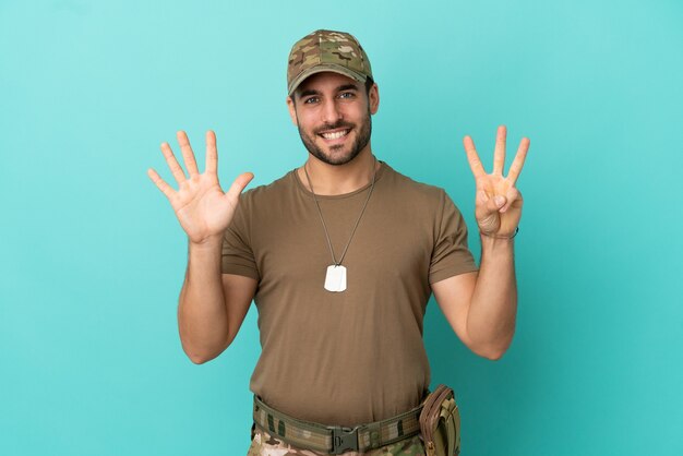 Militair met dog tag over geïsoleerd op blauwe achtergrond die acht met vingers telt