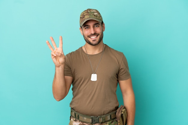 Militair met dog tag over geïsoleerd op blauwe achtergrond gelukkig en drie tellen met vingers