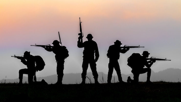 Foto militair of soldaat silhouetten op zonsondergang hemelachtergrond, volledig uitgeruste en gewapende soldaat staande op silhouetten milieu in zonsondergang.