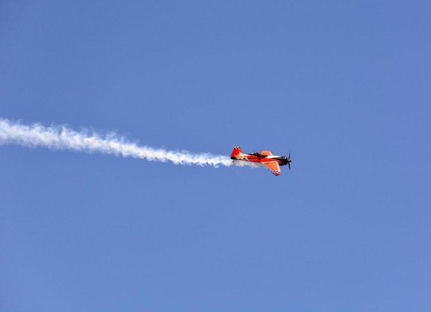 Militair vliegtuig vliegt binnen met rook in de blauwe lucht