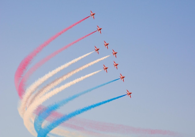 Militaire gevechtsvliegtuigen vliegen in een groep met rook in de blauwe lucht