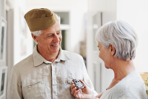 Militaire medaille en eer met een ouder echtpaar in hun huis dat zich nostalgisch voelt over legerdienst Oorlogsheldonderscheiding of herinnering en een volwassen man soldaat in een huis met zijn vrouw die zich patriottisch voelt