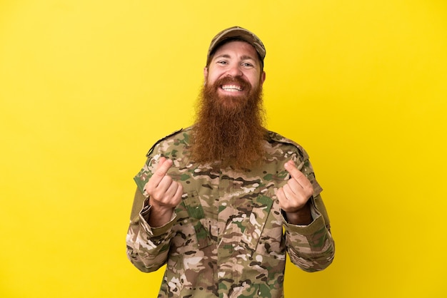 Foto militaire roodharige man over geïsoleerd op gele achtergrond geld gebaar maken