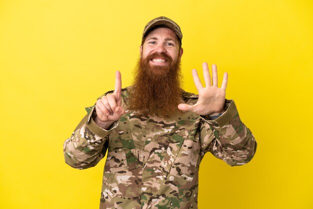 Militaire roodharige man over geïsoleerd op gele achtergrond zes tellen met vingers