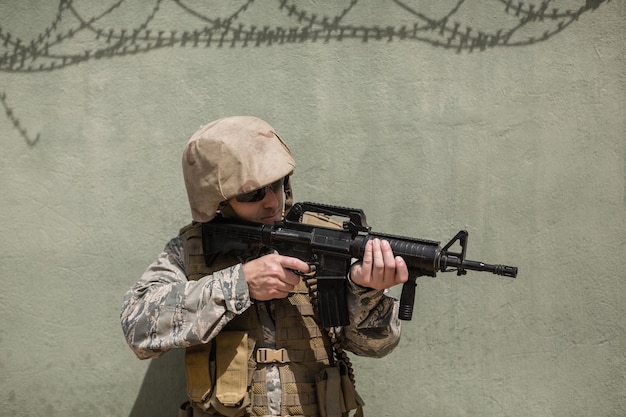 Militaire soldaat gericht met een geweer tegen betonnen muur in laarskamp