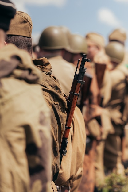 Photo military construction of soldiers during the reconstruction of hostilities in may, a narrow area of sharpness, focus on the rifle