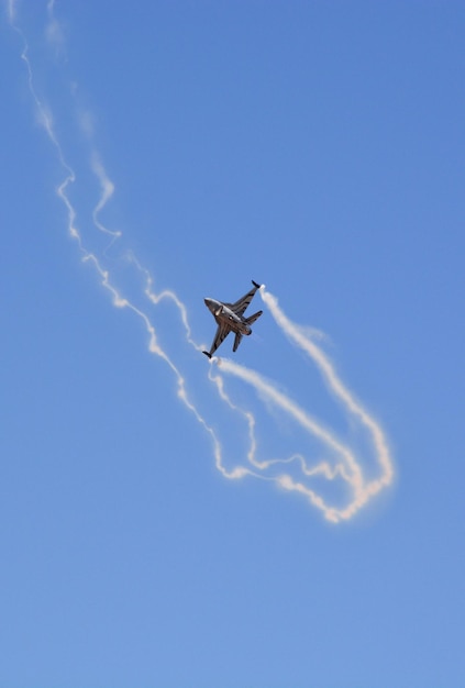 A military fighter jet is flying in the blue sky