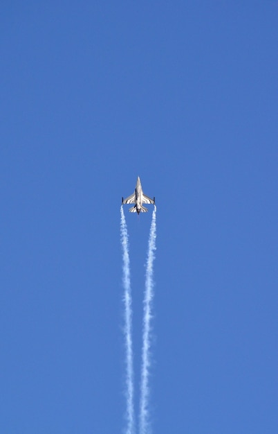 A military fighter jet is flying in the blue sky