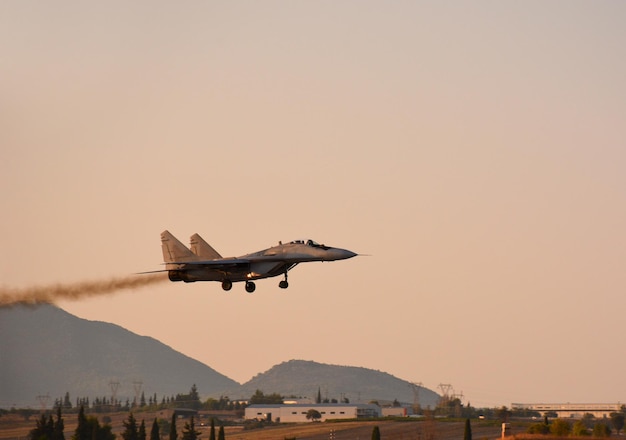 A military fighter plane lands at sunset