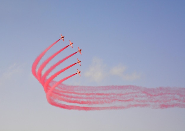 Military fighter planes fly in a group with smoke in the blue sky