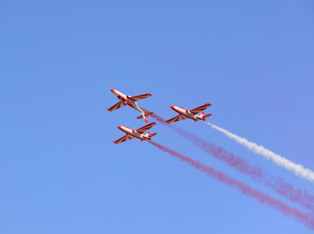 Military fighter planes fly in a group with smoke in the blue sky