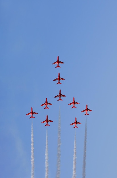 Military fighter planes fly in a group with smoke in the blue sky