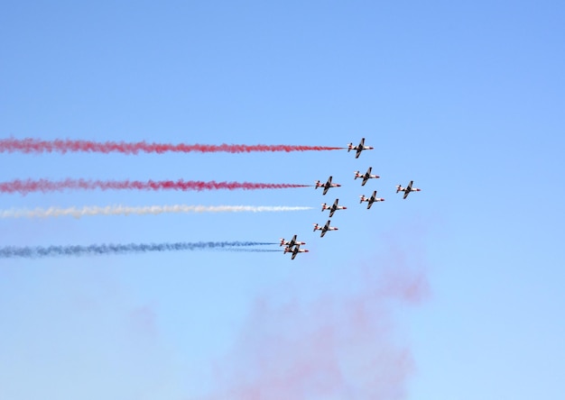 Military fighters planes fly in a group with smoke in the blue sky