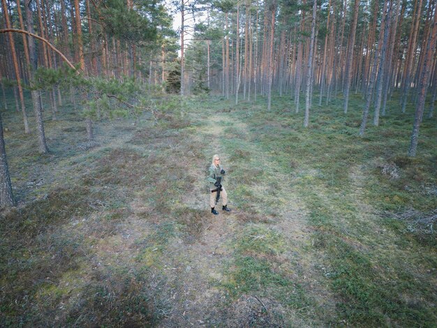 Foto una ragazza militare con un fucile con un silenziatore in una foresta di pini