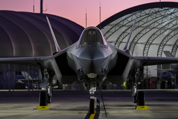 A military jet is parked on the tarmac at dusk.