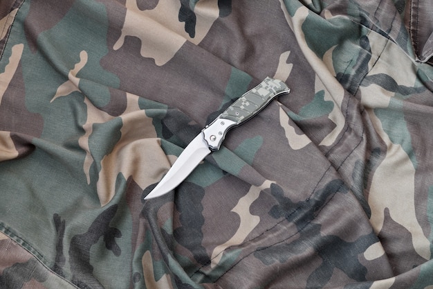 Military knife on army camouflage clothes