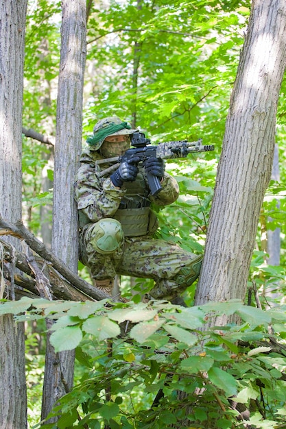 A military man in the forest sits in ambush. Soldier's machine gun and clothes