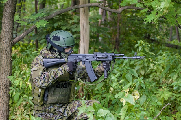 Военный в лесу с автоматом. Подготовка военных к бою.