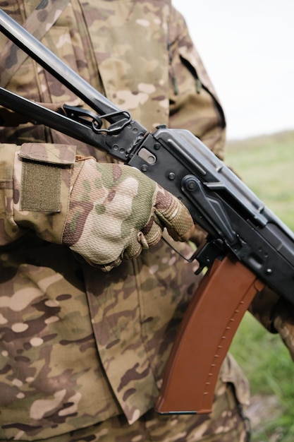 Military man holding AK47 with tactical gloves