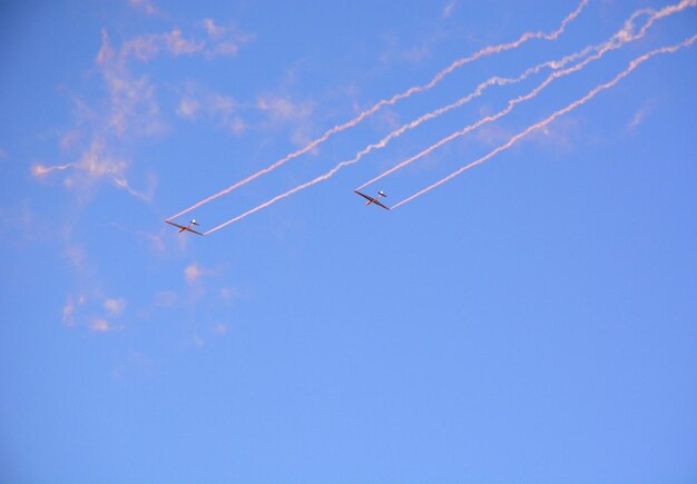 軍用機が青空に煙を上げて飛んでくる