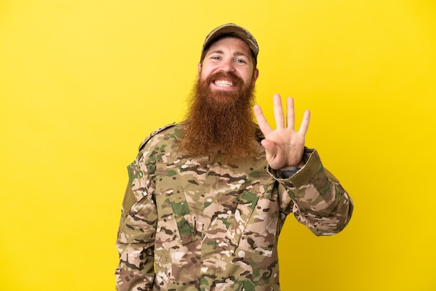 Military Redhead man over isolated on yellow background happy and counting four with fingers