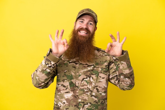 Military Redhead man over isolated on yellow background showing an ok sign with fingers