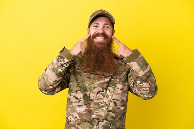 Military Redhead man over isolated on yellow background smiling with a happy and pleasant expression