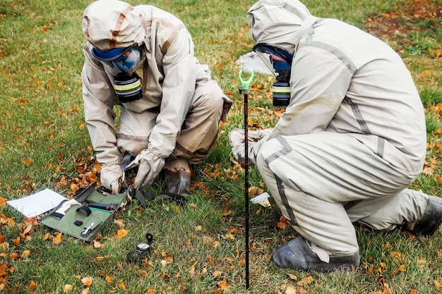 Military scientists in protective suits check radiation levels in open areas outside Measurement of environmental pollution