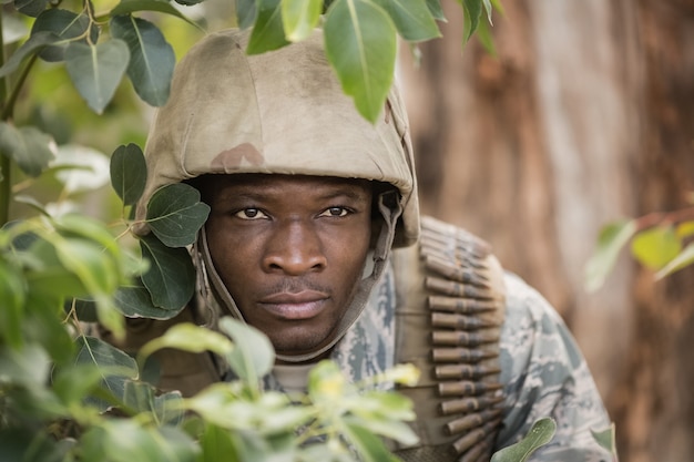 Photo military soldier hiding behind trees in boot camp