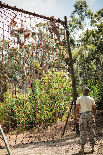 Military soldiers climbing rope during obstacle course