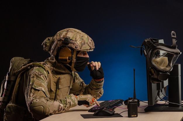 L'esercito in uniforme seduto al computer conduce una guerra informatica