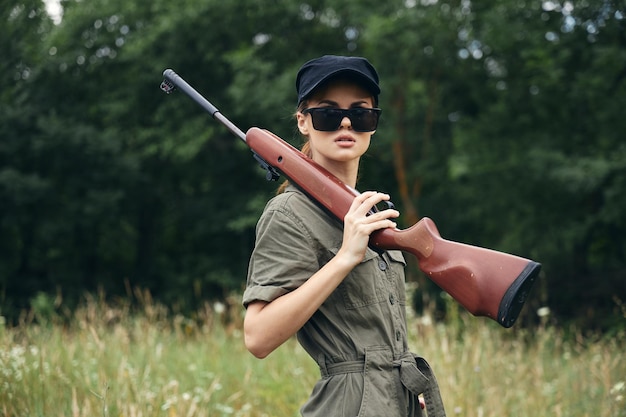 Military woman In dark sunglasses hunting lifestyle weapon green leaves closeup