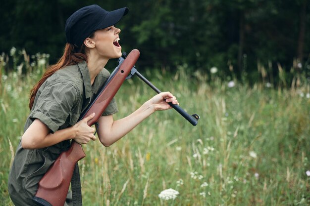 兵士の女性は手に楽しい武器を持って新鮮な空気緑の葉森の背景を再充電します