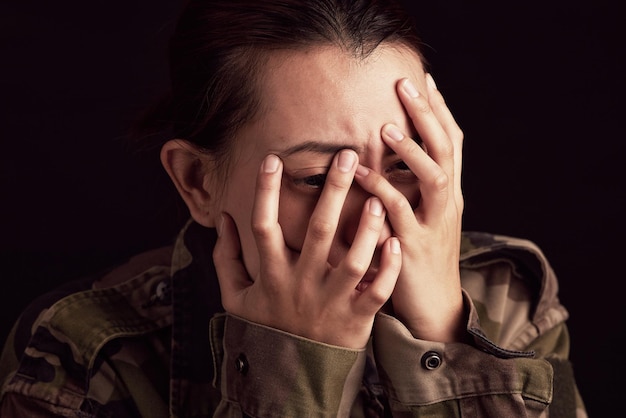 Military woman mental health and crying in studio for depressed anxiety and stress in war clothes Female soldier sad ptsd or trauma memory from army by black background with depression in Ukraine