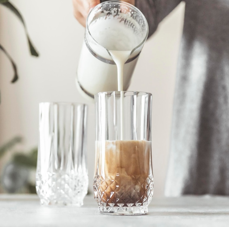 Photo milk being poured into coffee cup on table