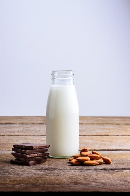 Milk in bottle, chocolate and almond on wooden