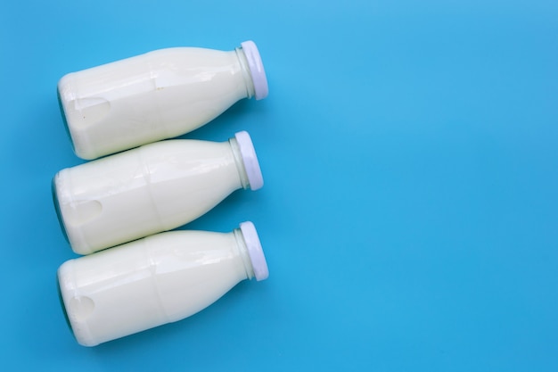 Milk bottles on blue background. Copy space