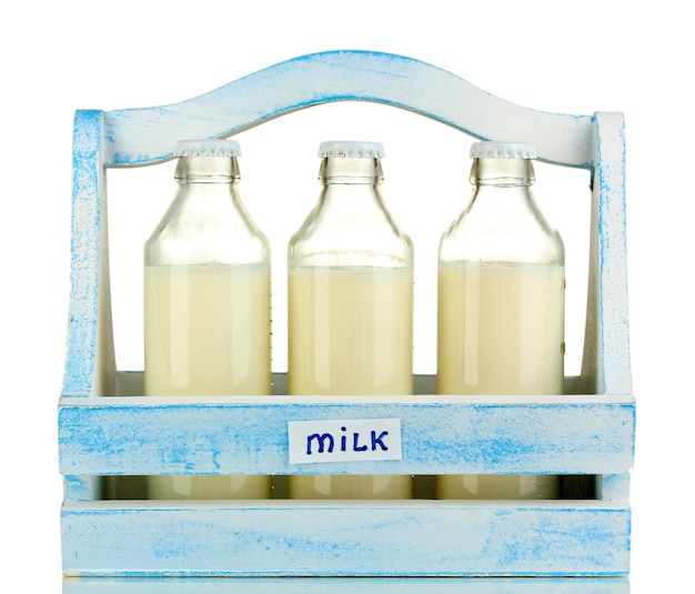 Photo milk in bottles in wooden box isolated on white
