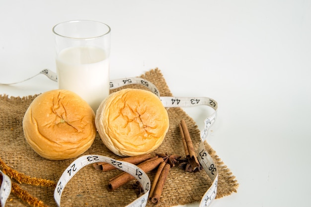 milk and bread with measuring tape for diet on white background