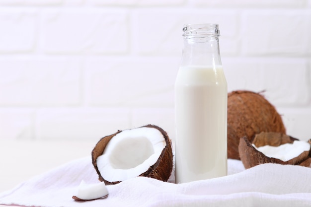 Latte e noci di cocco rotte sul tavolo latte vegetale una bevanda vegetariana