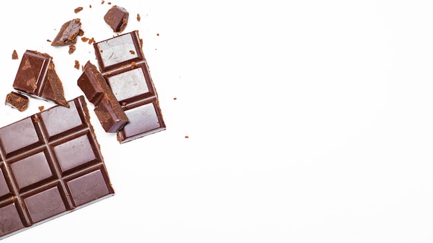 Milk chocolate bar pieces on white isolated background. Top view. Copy space. 