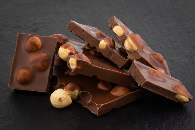 Milk chocolate pieces with nuts on a dark background.