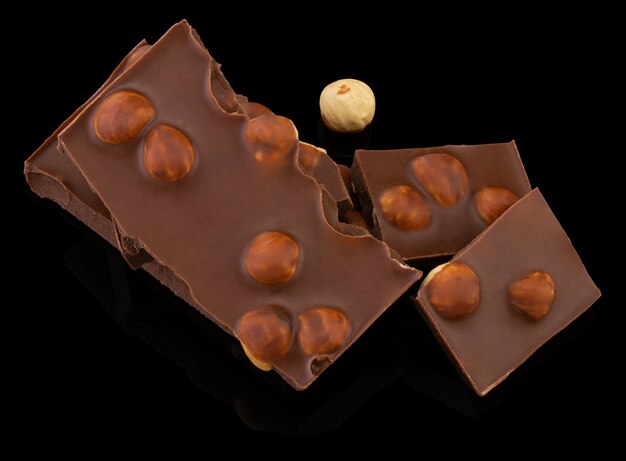 Milk chocolate pieces with nuts on a dark background.