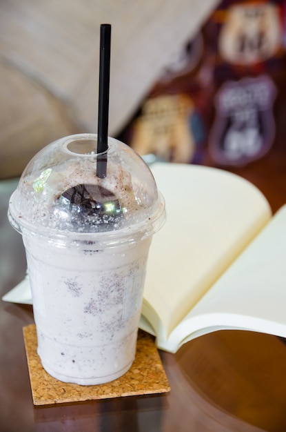 Milk chocolate smoothie with open book on glass table