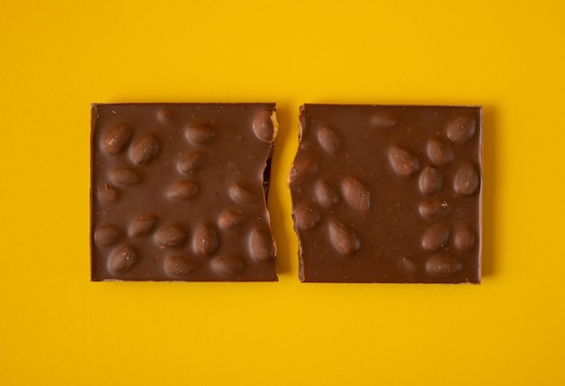 Milk chocolate with whole nuts on a yellow background