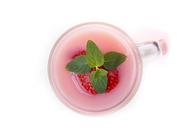 Milk cocktail with strawberry with mint leaves in a clear glass and berries on a light background.